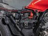 Wiring routed along the frame of a red-tank motorcycle, the fused red lead reaching the battery terminal under the seat