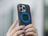 Close-up of two hands holding the MAG case, its bright blue magnetic ring standing out against the black back