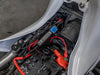Blue switch facing up as the adaptor sits on a frame rail beneath white bodywork, wired to the battery&