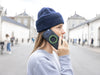 Woman in a blue beanie taking a call on a city street, the case&